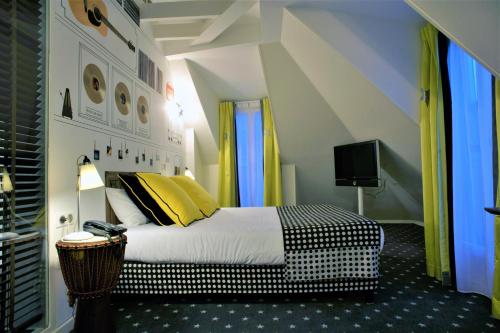 a bedroom with a bed with yellow and black pillows at Hôtel du Triangle d'Or in Paris