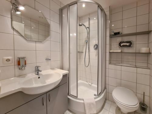 ein Bad mit einer Dusche, einem Waschbecken und einem WC in der Unterkunft Hotel am Hachinger Bach by Blattl in Neubiberg
