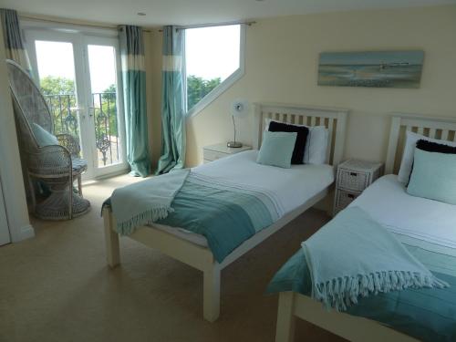 ポートランドにあるChesil View Houseのベッドルーム1室(ベッド2台付)、バルコニーが備わります。