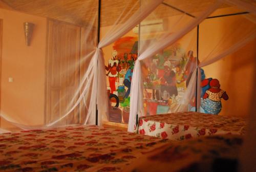 ein Schlafzimmer mit einem Himmelbett in der Unterkunft Baobab Soleil in Sindia