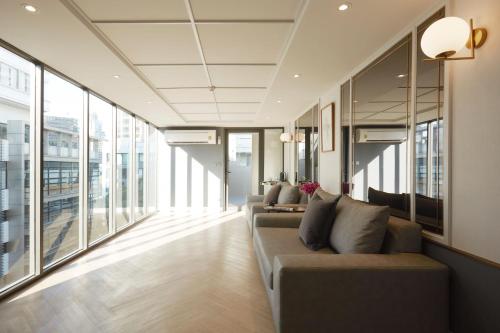 a living room with two couches and large windows at The Quarter Ploenchit by UHG in Bangkok