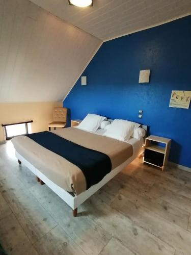 une chambre avec un grand lit avec un mur bleu dans l'établissement LES 4 VENTS, à Saint-Berain-sur-Dheune