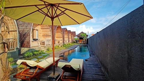 a pool with chairs and an umbrella next to a building at Tanhana Villa Canggu in Canggu