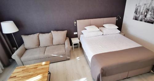 a small bedroom with a bed and a couch at Sky 17 Lux apartman in Zagreb