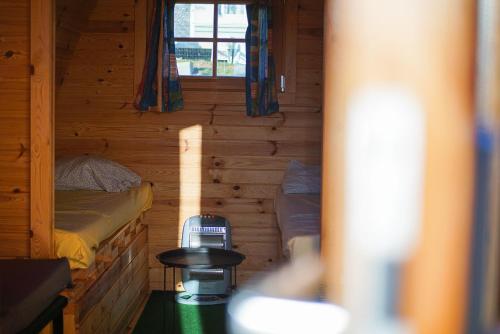Habitación pequeña con 2 camas en una cabaña de madera en Camping Le pommier rustique, en Yvoir