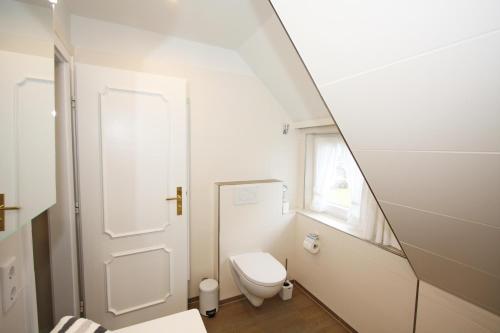 a bathroom with a white toilet and a mirror at C-Haus Cordula, App 41 in Wenningstedt