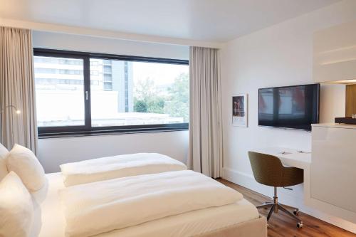 a hotel room with a bed and a desk and a window at Scandic Frankfurt Museumsufer in Frankfurt/Main