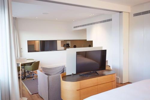 a bedroom with a tv on a dresser with a table at Scandic Frankfurt Museumsufer in Frankfurt/Main