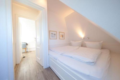 a white bed in a room with a window at C-Haus Constanze, App 46 in Wenningstedt