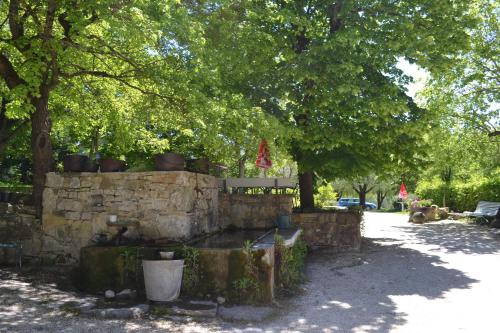 a stone wall with a bench and some trees at Auberge Les Sibourgs in Bourdeaux