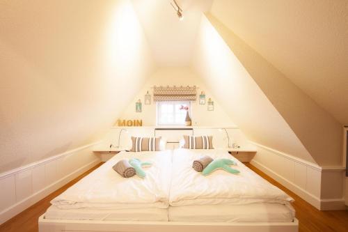 a bedroom with a white bed in a attic at SyltStern Haus Hasenkuhle in Wenningstedt