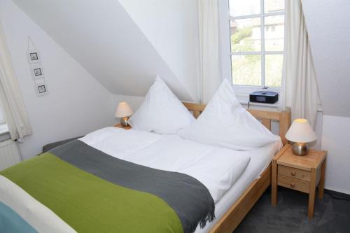 a bedroom with a bed with white and green sheets at LH Dwarslöper, App 3 in Wenningstedt