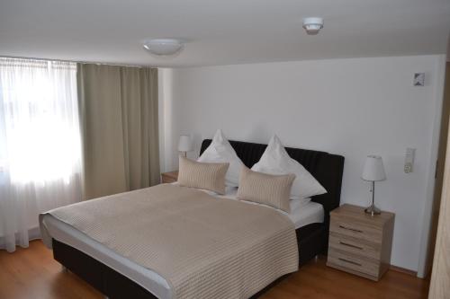 1 dormitorio con 1 cama grande con almohadas blancas en Pension Klitzeklein Zentrum, en Wertheim