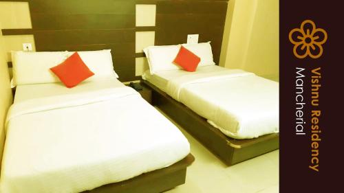 a bedroom with two beds with white and red pillows at Vishnu Residency Mancherial in Mancherāl