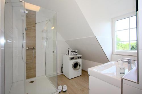 a bathroom with a shower and a washing machine at Jutta, App 6 in Wenningstedt