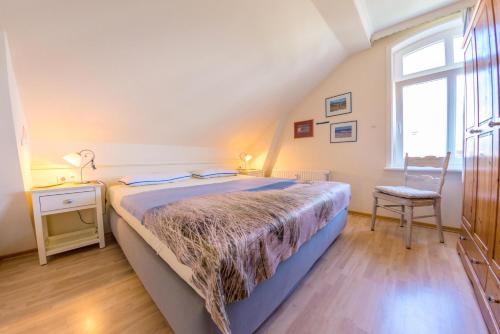 een slaapkamer met een bed, een stoel en een raam bij Sölring Hüs, App 4 in Wenningstedt