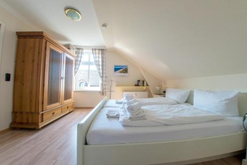 uma grande cama branca num quarto com uma janela em Sölring Hüs, App 3 em Wenningstedt