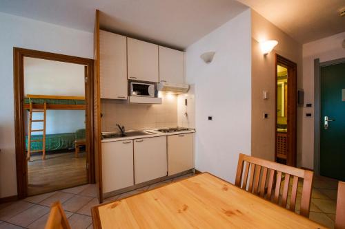 a kitchen with white cabinets and a wooden table at Residenza Del Sole in Gressoney-Saint-Jean