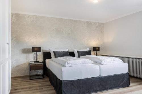 ヴェニングシュテットにあるHaus Weissenburg, Whg EG Ostの大きな白いベッドと2つのランプがある寝室