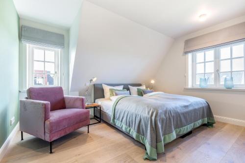 een slaapkamer met een bed en een stoel bij Haus Nuudt in Wenningstedt