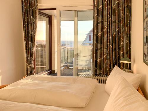 1 dormitorio con cama y ventana grande en Schloss am Meer, App 9, en Wenningstedt