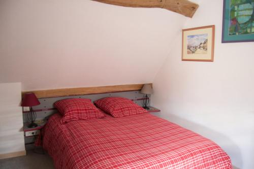 a bedroom with a red bed with two red pillows at Au Fond du Jardin Maison d'hôtes in Saint-Saëns