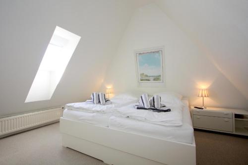 ein weißes Schlafzimmer mit einem großen weißen Bett mit zwei Kissen in der Unterkunft Am Heidepark, App 5 G in Wenningstedt-Braderup