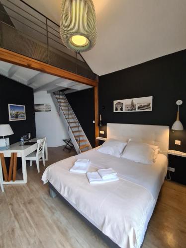 une chambre avec un grand lit blanc et un escalier dans l'établissement Logis Hôtel La Chaize, à Noirmoutier-en-l'lle