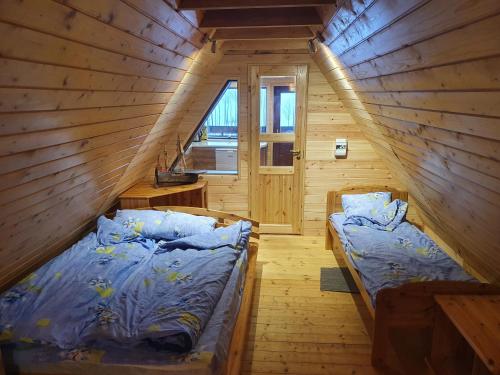 two beds in a wooden room with a window at Päevatalu Camping in Vilusi