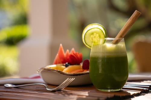 um copo de suco verde ao lado de uma tigela de frutas em Itz'ana Resort & Residences em Aldeia de Placencia