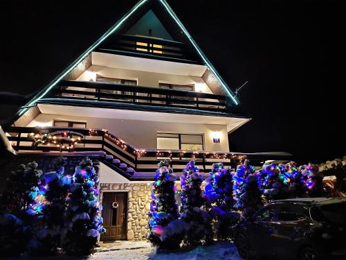 a house with christmas lights in front of it at Pokoje u Teresy in Czarna Góra