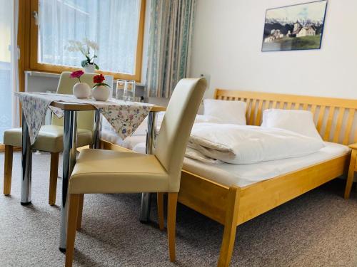 a bedroom with a bed and a table with chairs at Pension Anneliese in Rauris