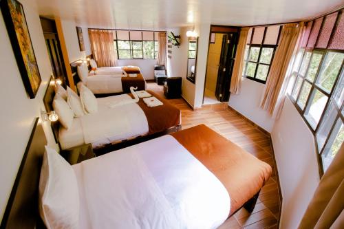 a bedroom with two beds in a room with windows at Samananchis Machupicchu in Machu Picchu