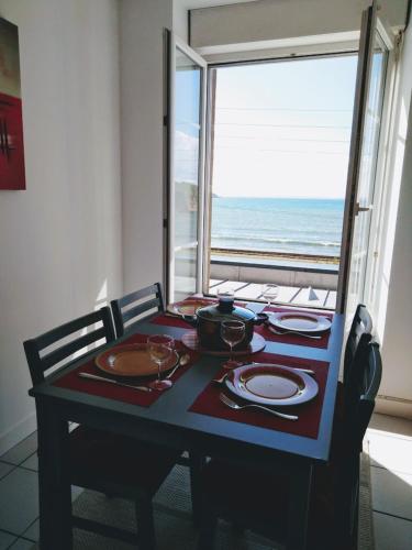 a table with plates and dishes and a view of the ocean at L'APPART DU RIS in Douarnenez