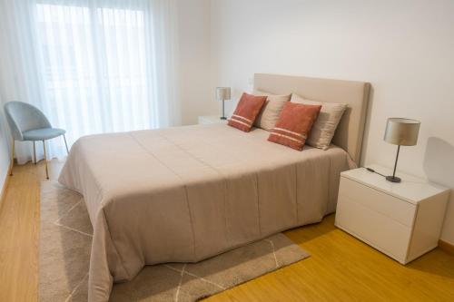 a white bedroom with a large bed with orange pillows at Perola Mar in Nazaré