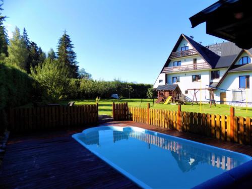 a swimming pool in front of a house at Pokoje u Teresy in Czarna Góra