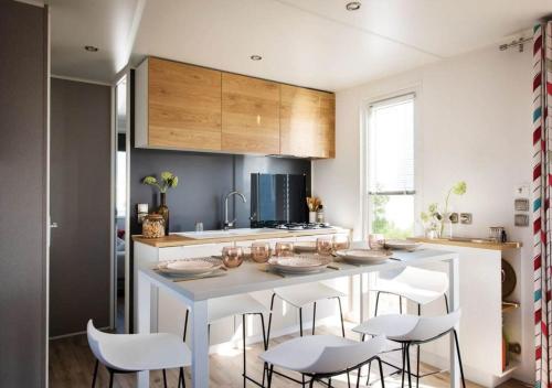 - une cuisine avec une table blanche et des chaises blanches dans l'établissement Vacances en Chalet ou Mobil-home chez Camp'in Pirellu, à Porto-Vecchio