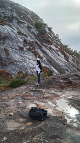 a person standing on a rocky hill with a backpack at Wayanad Three Roots Holiday Home Resort in Sultan Bathery