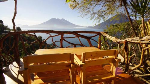 a wooden table and chairs on a deck with a view of the ocean at EL PICNIC ATITLÁN in Tzununá