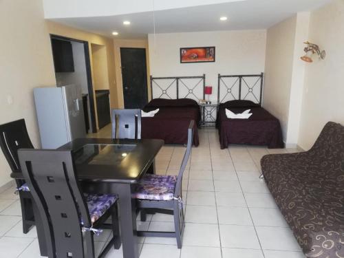 a living room with a table and chairs and a bedroom at Hotel Las Torres Gemelas Acapulco in Acapulco