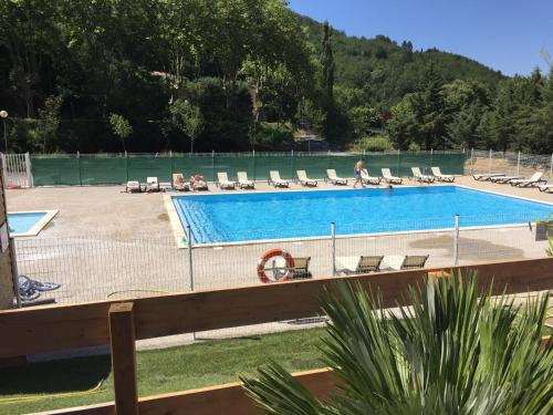 a swimming pool with chairs and a fence at Camping La Bernede in Rennes-les-Bains