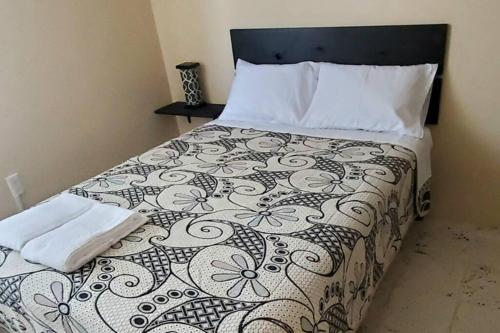 a bedroom with a bed with a black and white comforter at Todo al alcance de tu mano... Esmeralda in Celaya
