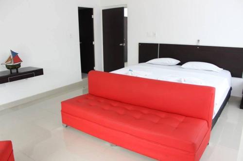 a red couch in a room with a bed at Hotel Cacique Guaicani in Melgar