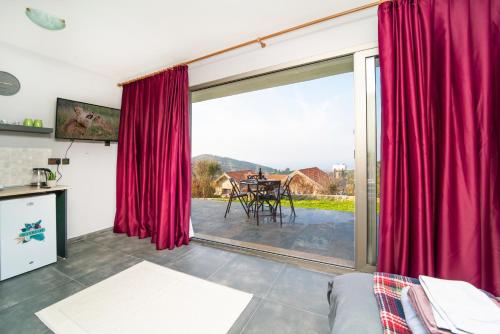 a living room with a large window with red curtains at Chardonnay Guest Studio Rooms with Great view for nature lovers in Kérynia