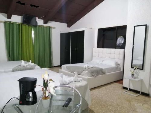 Casona del Valle في Potrerillos: غرفة نوم بسريرين مع ستائر خضراء وطاولة زجاجية