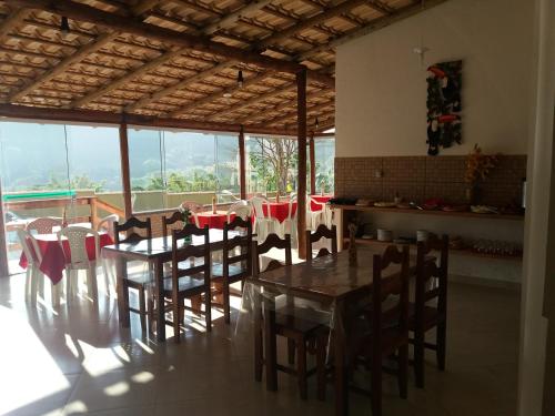 a dining room with a table and chairs and windows at Aconchego Canastra Hotel in Vargem Bonita