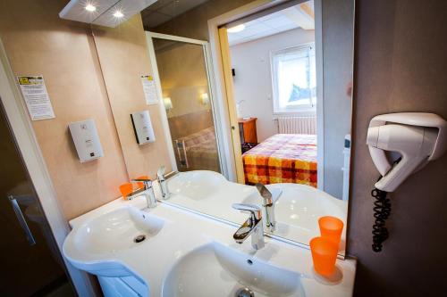 La salle de bains est pourvue d'un lavabo blanc et d'un miroir. dans l'établissement Logis Hôtel Belle Vue, à Les Ancizes-Comps