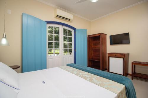 a bedroom with a white bed and a window at Pousada Eclipse Paraty in Paraty