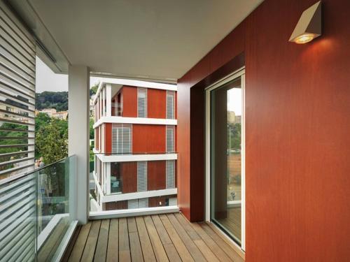 einen Balkon mit einer roten Wand und einem großen Fenster in der Unterkunft Maison Marquet in Cap d'Ail