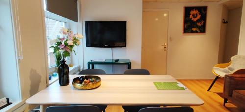 a living room with a table and a vase of flowers at Appartementen Dorp & Duin in Egmond aan Zee